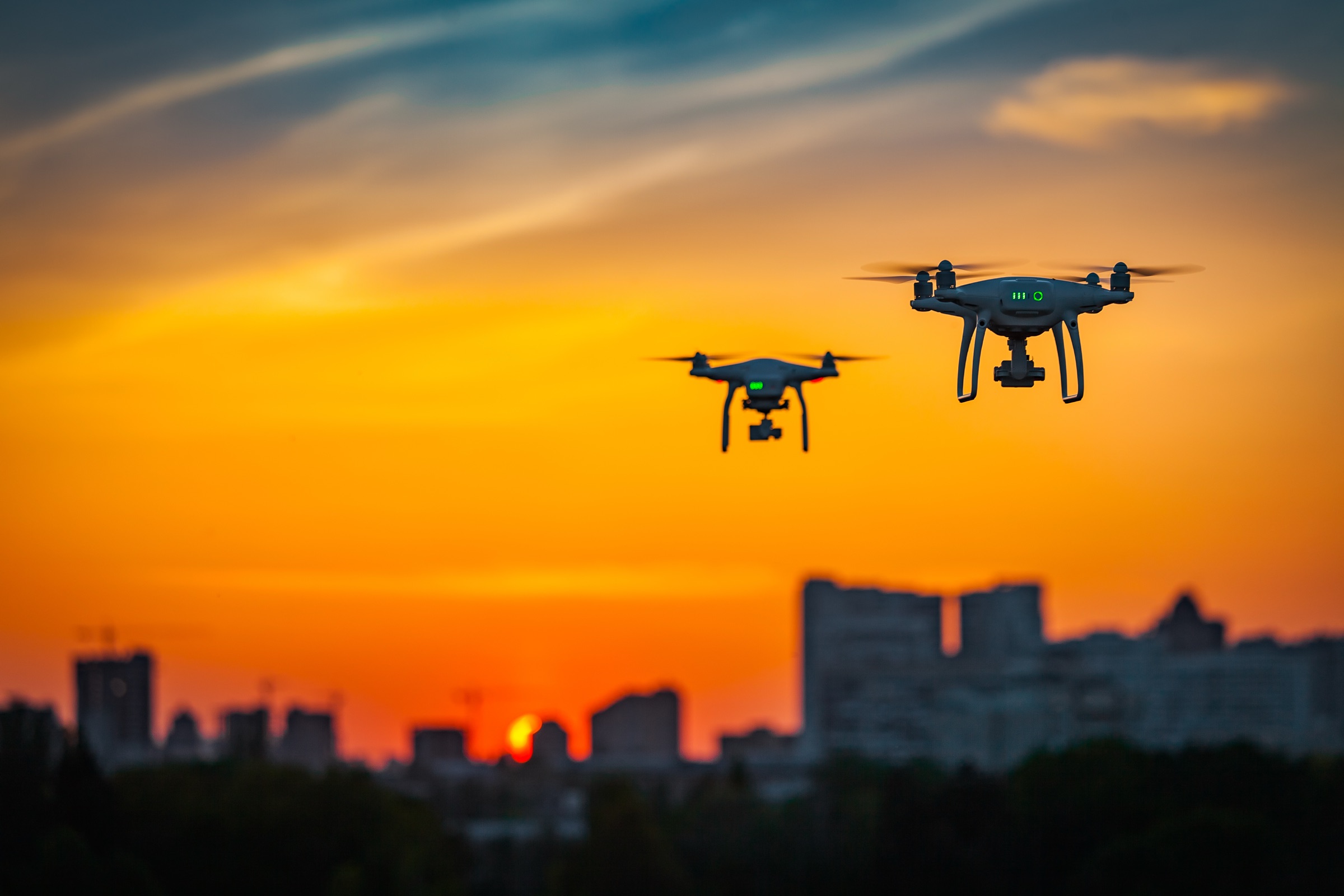 Two delivery drones flying over an urban skyline